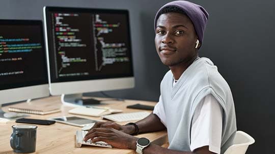 Ghanaian software professional working at a modern coding workstation
